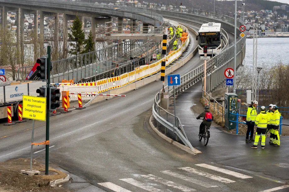 Arbeidere i gule klær jobber i gangveien på Tromsøbrua