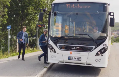 Buss som stopper ved holdeplass i sentrum og slipper på passasjerer.