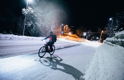 Vintersyklist i mørket på snødekt vei.