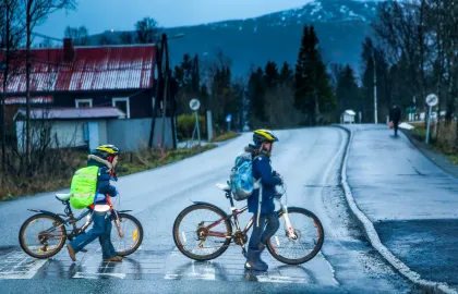 To barn leier sykkel i gangfelt over vei