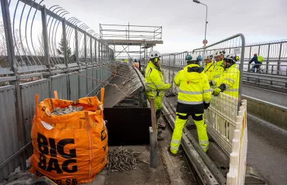 Arbeidere i gule klær jobber i gangveien på Tromsøbrua