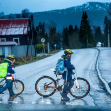 To barn leier sykkel i gangfelt over vei