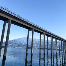 Tromsøbrua med gående i gangfeltet på sørlig side